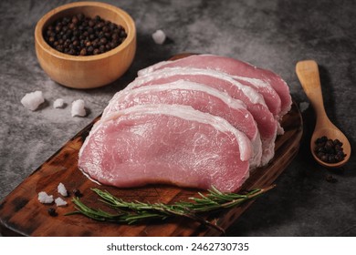 Close-up Raw pork loin preparing to cook on a wooden cutting board with rosemary, pepper, salt seasoning - Powered by Shutterstock