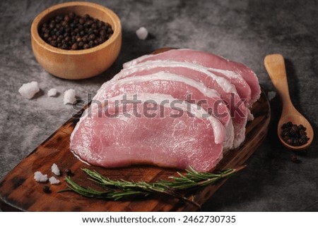 Close-up Raw pork loin preparing to cook on a wooden cutting board with rosemary, pepper, salt seasoning