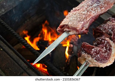 Close-up Raw Rump Steak And Pork On The Right And Flames In The Background. The Traditional Churrasco Gaúcho, Brazilian Barbecue.