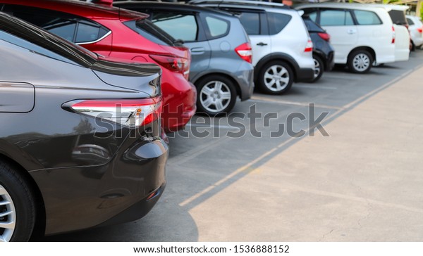 Closeup of rear, back\
side of black car with  other cars parking in parking lot under the\
roof in bright sunny day. The mean of simply transportation in\
modern world.