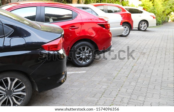 Closeup of rear, back side of black car with  other\
cars parking in outdoor parking area with natural background in\
sunny day.