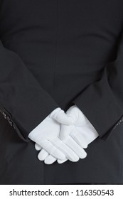 close-up rear side of a waiter wearing gloves with hands clasped