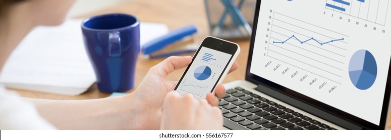 Close-up Rear View Of Business Woman Working In Office On Pc Holding Smartphone And Looking At Screen With Diagrams, Using Mobile Phone And Laptop. Horizontal Photo Banner For Website Header Design