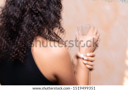 A closeup and rear view of a girl suffering from Parkinson's disease, violently trembling and holding her wrist trying to be steady, involuntary movements symptomatic of the disease.