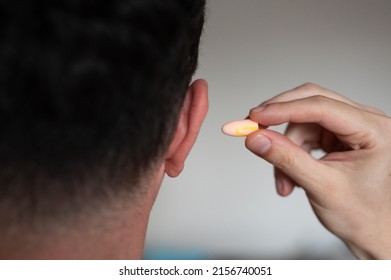 Close-up, Rear View Of Man's Hand Putting Foam Earplug In The Ear