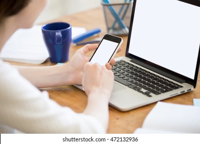 Close-up rear view of young business woman working in office interior on pc, holding smartphone, looking at screen. Office person using electronic devices, mobile phone and laptop, messaging, texting - Powered by Shutterstock