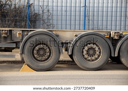 Close-up of rear wheels of a container trailer. Heavy transport detail, logistics, cargo transportation, freight industry and commercial vehicle concept.