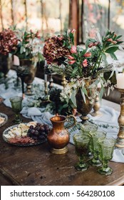 Closeup Of Reception Table Decorated By Grey Vintage Cloth, Candles, Bouquets Of Hydrangea And Greenery, Green Glasses And Wine. Windows On Background. Loft. Wedding. Decor