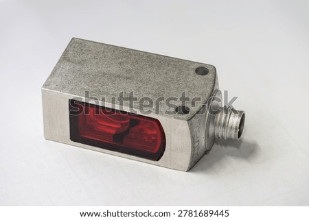 Close-up of a rectangular optical sensor with a metallic housing.