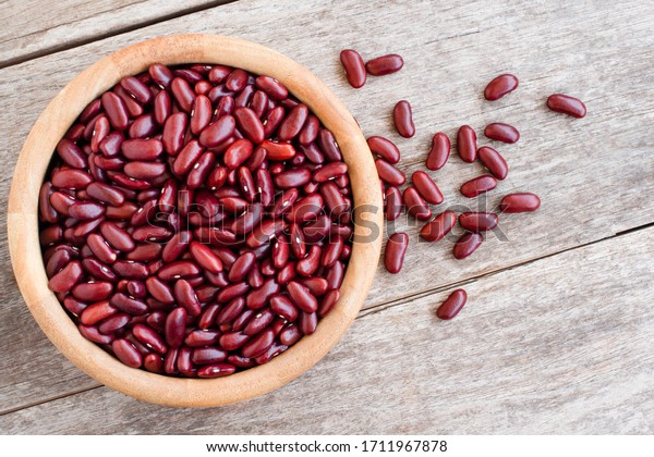 Closeup red bean or\
kidney beans in wooden bowl isolated onwood table background. Top\
view. Flat lay.
