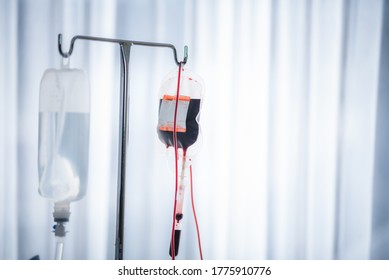 Close-up Of Red Blood Bag And Normal Saline Hanging In Hospital Ward 