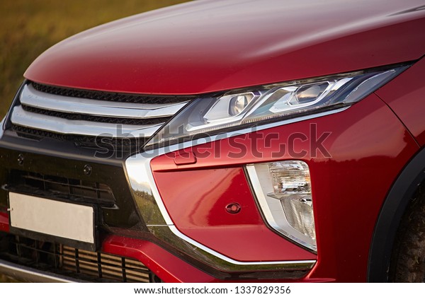 Close-up of a red car with\
a headlight, fog lamp bumper in the summer. Modern parts and\
technologies