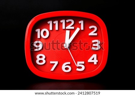 Close-up of red clock time lapse on black background. A red wall clock running fast.