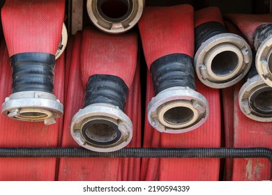 Closeup Of Red Coiled Water Hoses With Metal Connections On A Fire Truck Or Fire Engine. Firefighters Equipment.