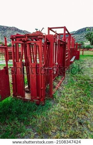 A closeup of Red colored Cattle squeeze chute on farm in Texas