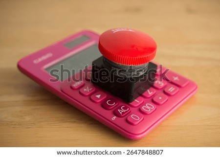 Closeup red emergency button on calculator background. Financial crisis, bankrupt, loss, refinancing, debt restructuring, stop payment, risk management and so on concept.