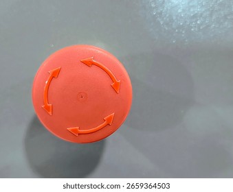 Close-up of a red emergency stop button with circular arrows, mounted on a metallic surface, used for industrial safety and machine shutdown in case of emergencies.