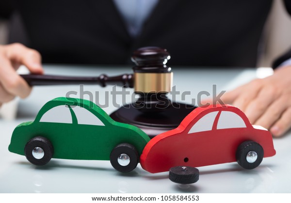 Close-up Of Red And Green Car Crash In Front Of\
Judge Holding Gavel