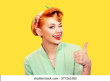 Closeup red head young woman pretty pinup girl green button shirt giving thumbs up sign gesture looking at you camera isolated yellow background retro vintage 50's style. Human emotions body language