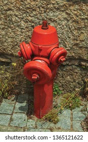 Close-up of red hydrant next to stone wall on a setts pavement at Seia. On foothill mountains, this friendly town in eastern Portugal is also known for its delicious artisanal cheese.