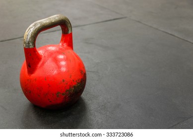 Close-up Of Red Kettle Bell On Black Gym Floor
