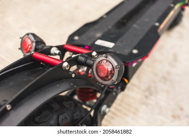 Closeup of red LED brake lights of a light duty electric scooter parked by the road.