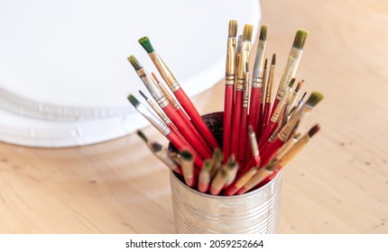 Close-up of red paint brushes in a metal jar. - Powered by Shutterstock