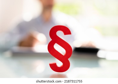 Close-up Of A Red Paragraph Symbol In Front Of Person Working At Workplace
