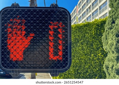 Close-up of a red pedestrian signal with a raised hand and countdown timer down to zero at a crosswalk in Santa Monica, California, USA
