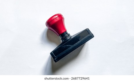 Close-up of red rectangular rubber stamp used in offices for administrative work, validation, and document certification.