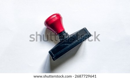 Close-up of red rectangular rubber stamp used in offices for administrative work, validation, and document certification.