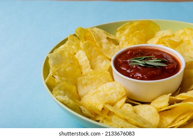 Close-up Of Red Sauce In Bowl Amidst Potato Chips Served In Plate On Blue Background. Unaltered, Unhealthy Food, Snack, Dipping Sauce, Crunchy, Salty Snack And Savory Food.