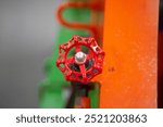 Close-up of a red valve handwheel against a colorful industrial background. The robust metal design ensures precise control in industrial piping systems