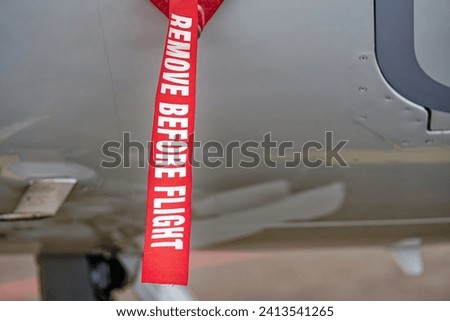 Close-up red and white fabric ribbon with remove before fligth text at Swiss Airport Zürich Kloten on a cloudy winter day. Photo taken January 15th, 2024, Zurich, Switzerland.