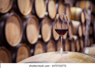 Closeup red wine glass on background of wooden oak barrels stacked in straight rows in order in cellar of winery, vault. Concept professional degustation, winelover, sommelier travel - Shutterstock ID 1475710772