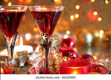 Closeup of red wine in glasses,candle lights, gift box,baubles and twinkle lights on background.