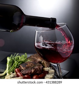 Closeup Of Red Wine Pouring Into Glass With Meat And Cheese