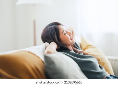 Closeup - Relaxed young asian woman enjoying rest on comfortable sofa at home, calm attractive girl relaxing and breathing fresh air in home, copy space. - Shutterstock ID 2132895665