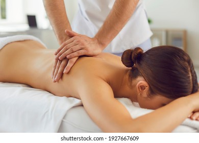 Closeup of relaxed young woman lying face down on massage table and enjoying remedial body massage done by professional masseur in spa salon or wellness center - Powered by Shutterstock