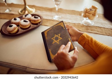 Close-up Of Religious Man Reading Hebrew Bible While Celebrating Hanukkah At Home.