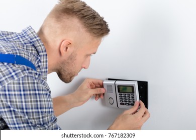 Close-up Of Repairman Installing Security System Against Wall