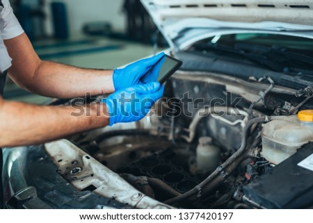 closeup of repairman using tablet in car service