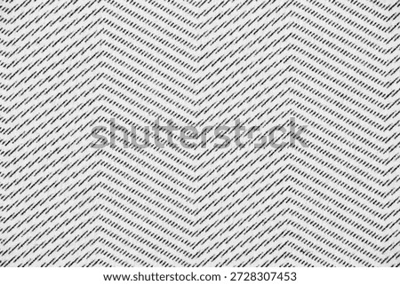 Close-up of a repeating chevron pattern formed by dotted black lines printed on white paper, showing fine ink texture.