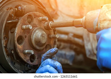 Close-up replacement of the old front brake disc, brake caliper and hub nut on a car raised on a lift with a pneumatic wrench in a car repair shop. Auto mechanic repair. - Powered by Shutterstock