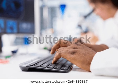 Closeup of research facility professional using PC software to evaluate genetic marker associated with disease risk. Worker types on keyboard, studies DNA strand mapping with genomics analysis program