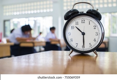 Closeup of Retro alarm clock with ten o'clock on table teacher in blur students exams classroom. Time is indefinite continued progress of existence. Education concept, selective focus. - Powered by Shutterstock