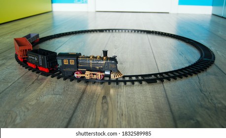 Closeup of a retro toy train on the circular track on the floor of colorful kids room