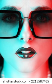 Close-up Retro Woman Style Portrait With Big Sunglasses And Make-up With Lipstick Looking At Camera In Red And Blue Color Split Effect. Selective Focus. Nose In Camera Focus. Futuristic Looking Style