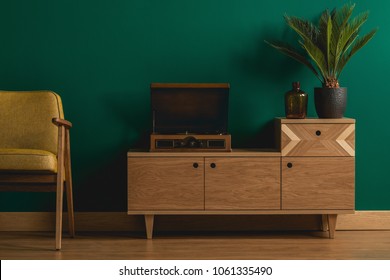 Close-up Of A Retro Wooden Dresser With A Hipster Record Player In A Minimalist Dark Green Living Room Interior