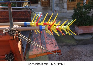 Close-up Of Rightly Colored Olive Picking Tools Sticking Out Of The Back Of A Scratched And Grungy Truck Bed Parked In A Small Greek Village